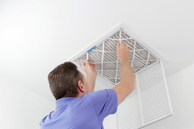 man replacing air filter in home 