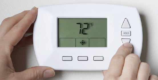 Person turning down the heat on their thermostat to 72 degrees. 