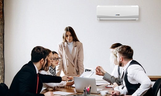 Staff in an office meeting with AC in background