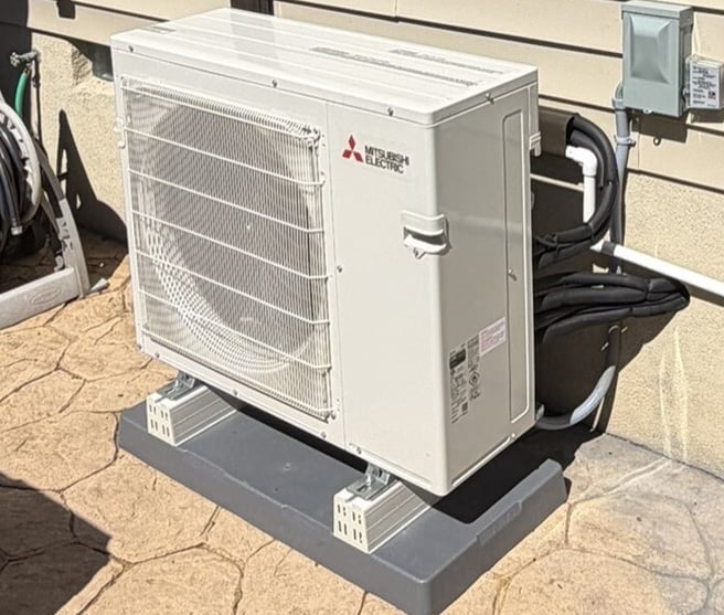 Mitsubishi Electric outdoor heat pump serving three indoor mini-split units in a split-level home.